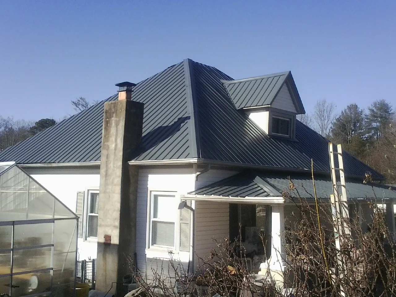 Dark blue standing seam metal roof on a white farmhouse with dormer — Slate & Tile Roof Repair by Roofing Brothers in Emmaus