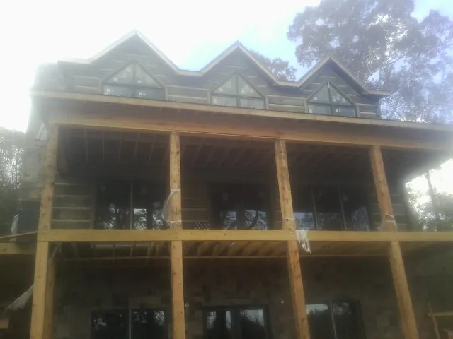 Dormers and porch framing on a large log home under construction — Roof Coating work by our crew in Emmaus