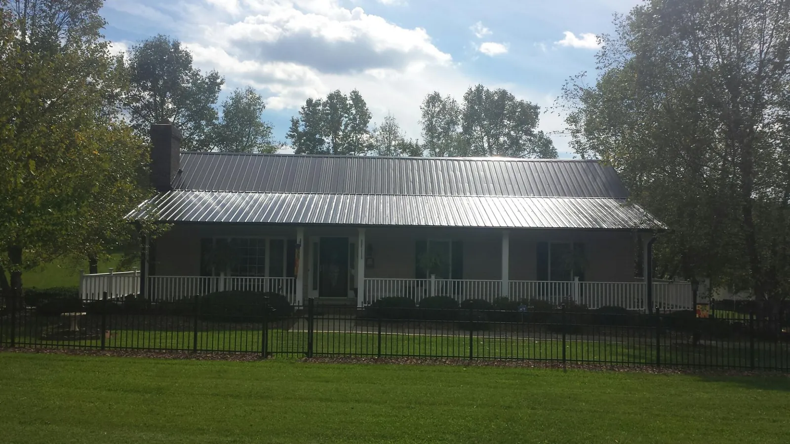 Gray metal roof on a brick ranch with a full width front porch — Gutter Guard Installation work by our crew in Emmaus