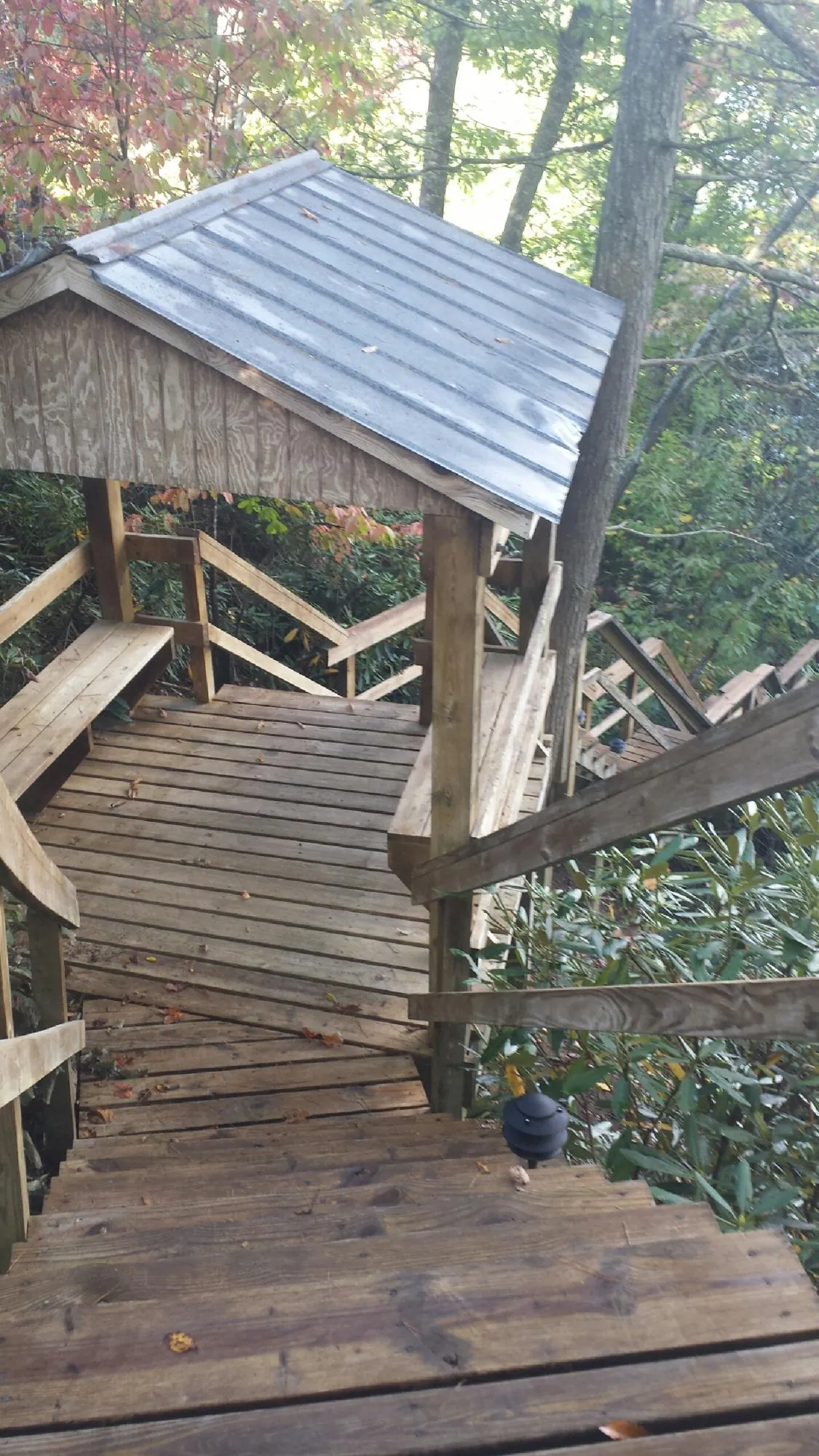 Metal roofed shelter over wooden steps on a wooded walkway — Skylight Repair & Installation work by our crew in Emmaus