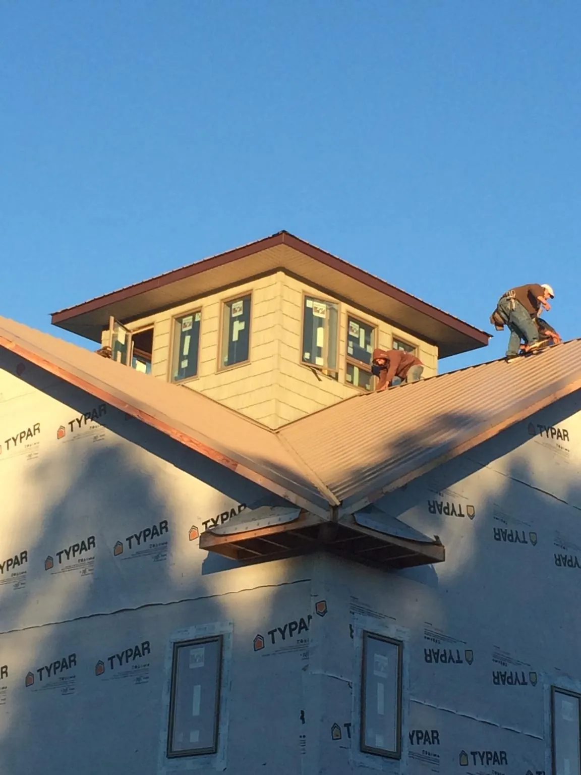Roofers working around a rooftop cupola on a new metal roof at sunset — Roof Waterproofing in Emmaus by Roofing Brothers